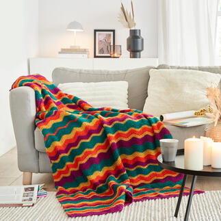 Bunte Decke auf einer Couch mit Kerzen und Zeitschriften.