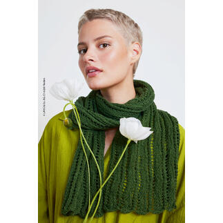 Frau mit kurzem Haarschnitt trägt einen grünen Schal und hält weiße Blumen.