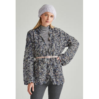 Frau in einer gehäkelten Jacke mit einem Gürtel, steht vor einem hellen Hintergrund.