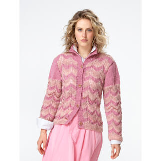 Frau steht in einer rosa Jacke mit Zopfmuster aus Landwolle.