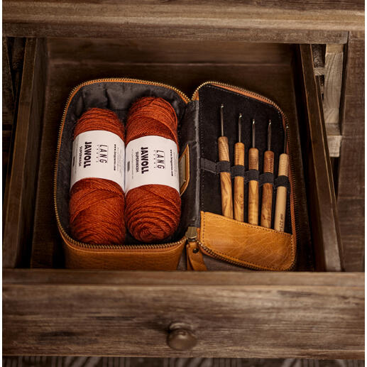 Muud Mappe Hope in Whisky-Farbe mit Garn und Werkzeugen im offenen Etui auf einem Tisch.