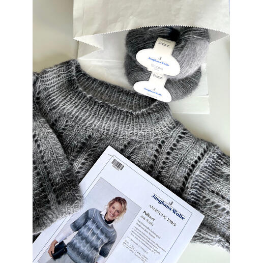 Grauer Pullover aus Scala, mit Garn und Anleitung daneben.