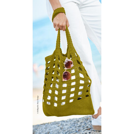 Olivenfarbene Tasche aus Bio-Baumwolle mit Sonnenbrille in der Hand.