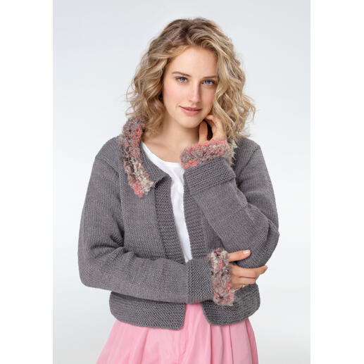 Frau in grauer Jacke aus Merino mit farbigen, pelzigen Akzenten, schaut direkt in die Kamera.