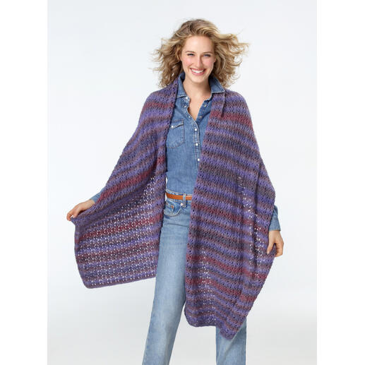 Frau präsentiert ein gemustertes Tuch aus Batique bei Tageslicht, im Freien.