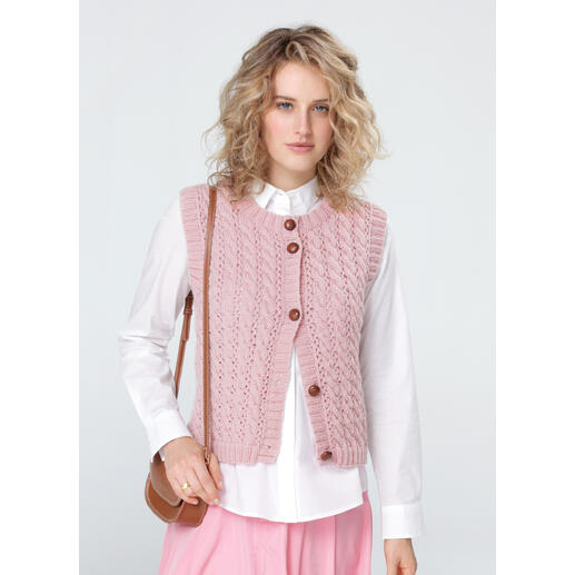 Frau in zart rosa Weste mit Knöpfen, kombiniert mit einer langen blauen Jeans.