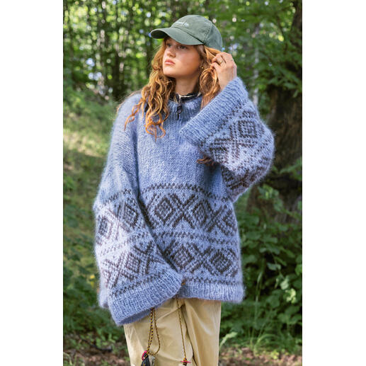 Frau trägt einen blauen oversized Pullover mit geometrischem Muster im Wald.