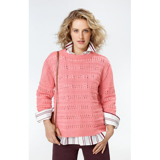 Frau in einem rosa Pullover mit Lochmuster, kombiniert mit Hemd und Tasche.