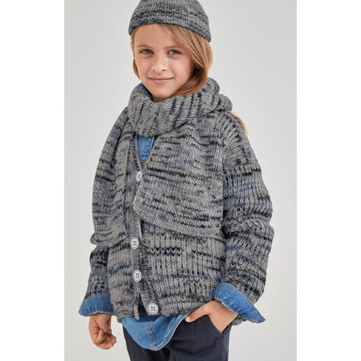 Junge in Cardigan aus Merino-Print mit Schal und Mütze, freundlich lächelnd.