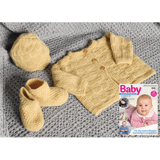 Gelbe Babyjacke, Mütze und Söckchen auf einem grauen Strickstück