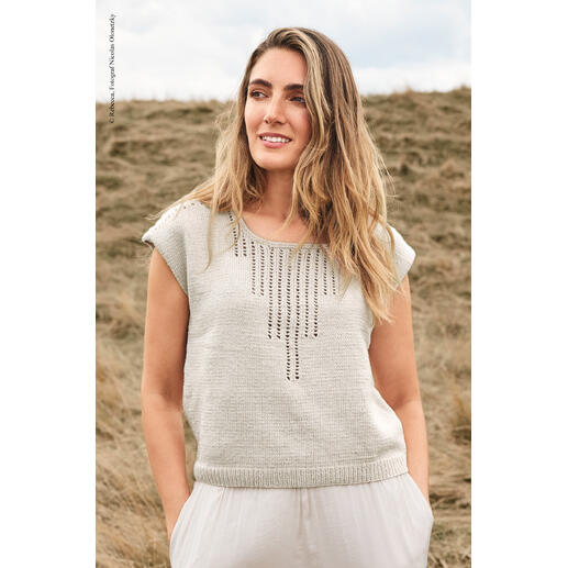 Frau in grauem Top aus Elida steht auf offenem Feld.