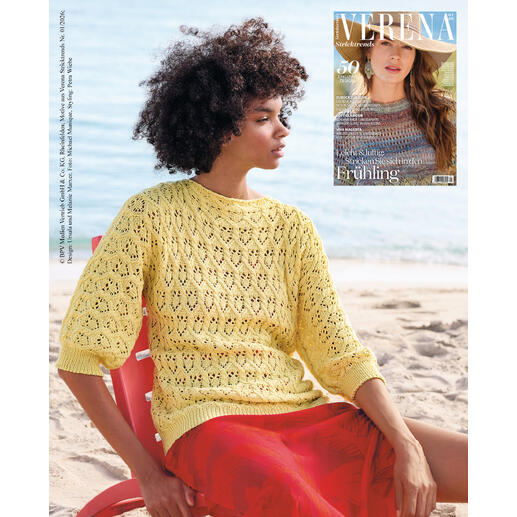 Frau trägt einen gelben Pullover am Strand, Zeitschrift im Hintergrund