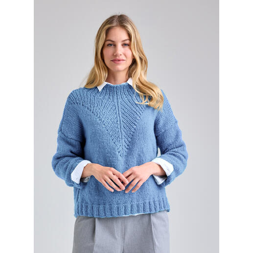 Frau trägt einen blauen Pullover aus NewWool mit V-Ausschnitt.