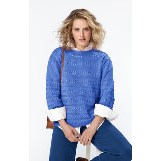Blauer Pullover aus Merino-Wolle, getragen von einer Frau mit lockigem Haar.