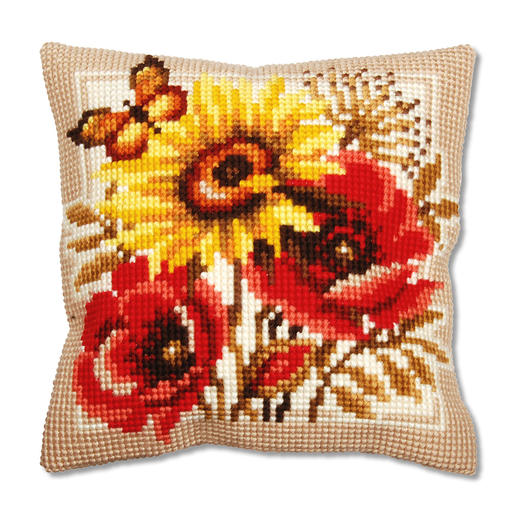 Kreuzstichkissen mit Sonnenblume und Mohnblumen auf braunem Hintergrund.