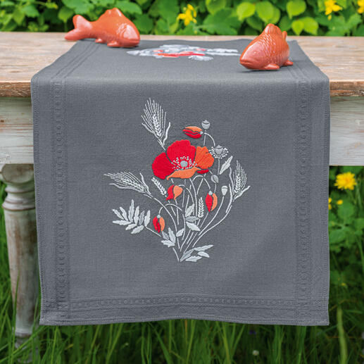 Tischläufer mit Mohnblumenmotiv auf einem Holztisch im Freien.