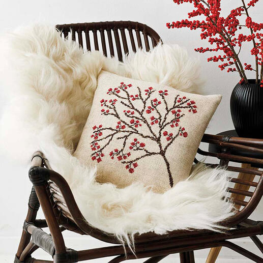 Kissenhülle mit winterlichen Beerenmotiven auf einem rattan Möbelstück.