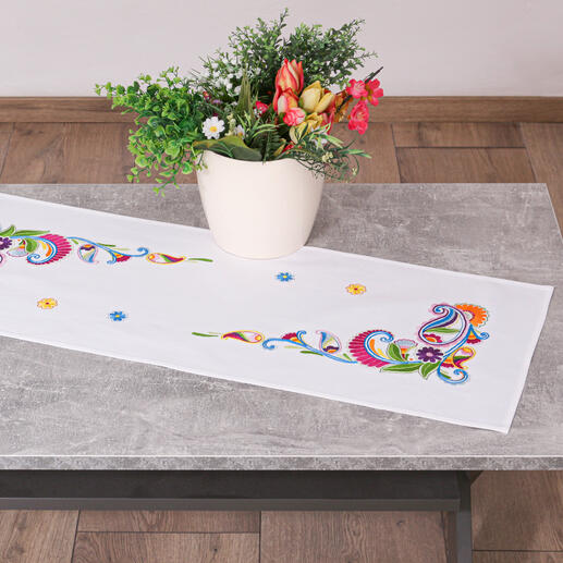 Tischläufer mit buntem Paisleymuster, dekoriert mit Blumenarrangement.