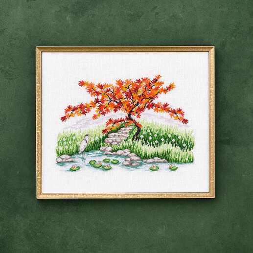 Kreuzstichbild eines Japanischen Ahorns und eines Reihers an einem Teich.