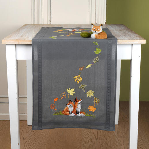 Tischläufer mit Füchsen in herbstlichen Farben auf einem grauen Tisch.