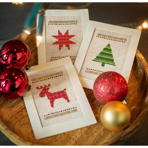 Drei Weihnachtskarten auf einem rustikalen Holztablett, umgeben von Weihnachtsdekoration.