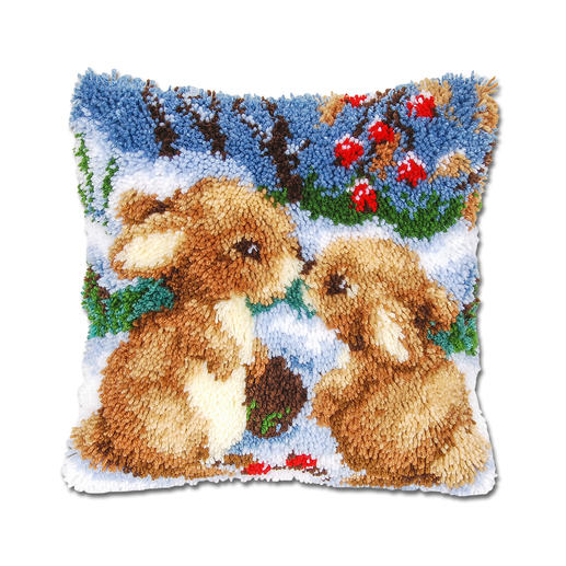 Knüpfkissen mit zwei niedlichen Hasen im Schnee, umgeben von roten Beeren.