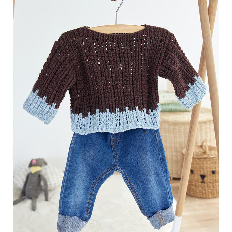 Brauner Babypulli aus Cotonara hängt an einem Kleiderbügel, neben Hose und Plüschtier.