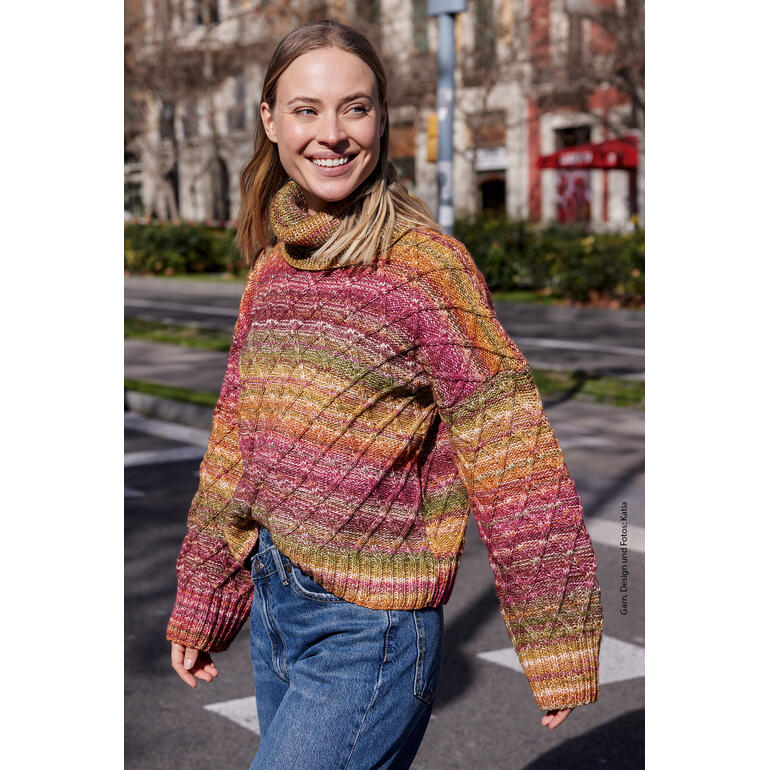 Frau in gemustertem Pullover aus Cotton-Merino, voller Lebensfreude, läuft über die Straße.