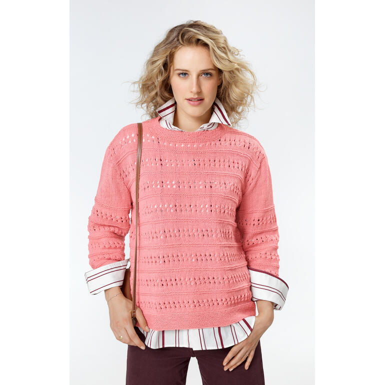Frau in einem rosa Pullover mit Lochmuster, kombiniert mit Hemd und Tasche.