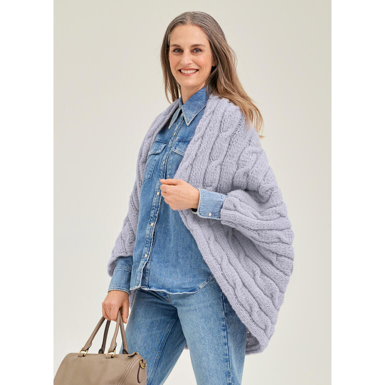 Frau in grauem, dickem Ärmelschal aus Wollmaterial, trägt eine Jeansjacke.