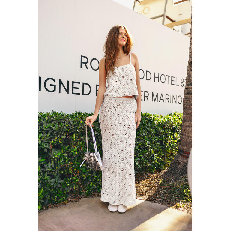 Frau in gestricktem Top und Rock aus Mandarin Petit posiert in der Stadt.