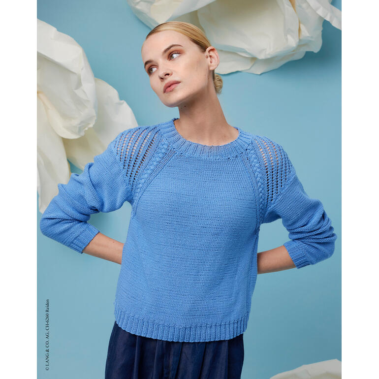 Frau in blauer Strickbluse vor einer blauen Wand mit großen Blumen im Hintergrund