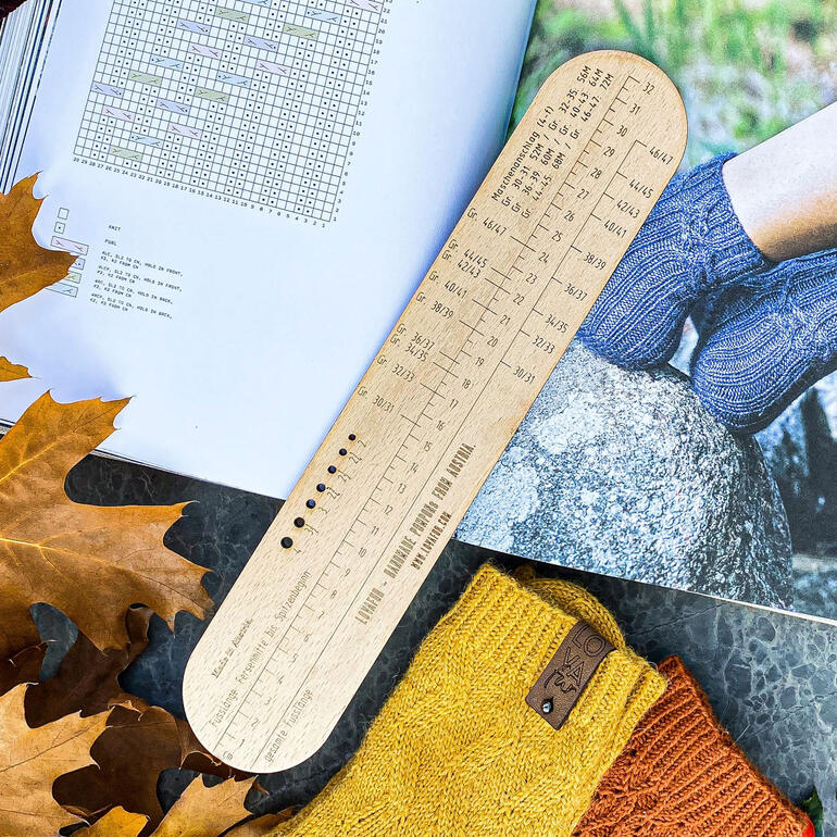 Sockenlineal für 4-fach Garne auf einem Tisch mit Laub.