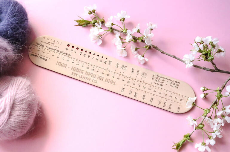 Sockenlineal für 6-fach Garne auf einem rosa Hintergrund mit Wolle.