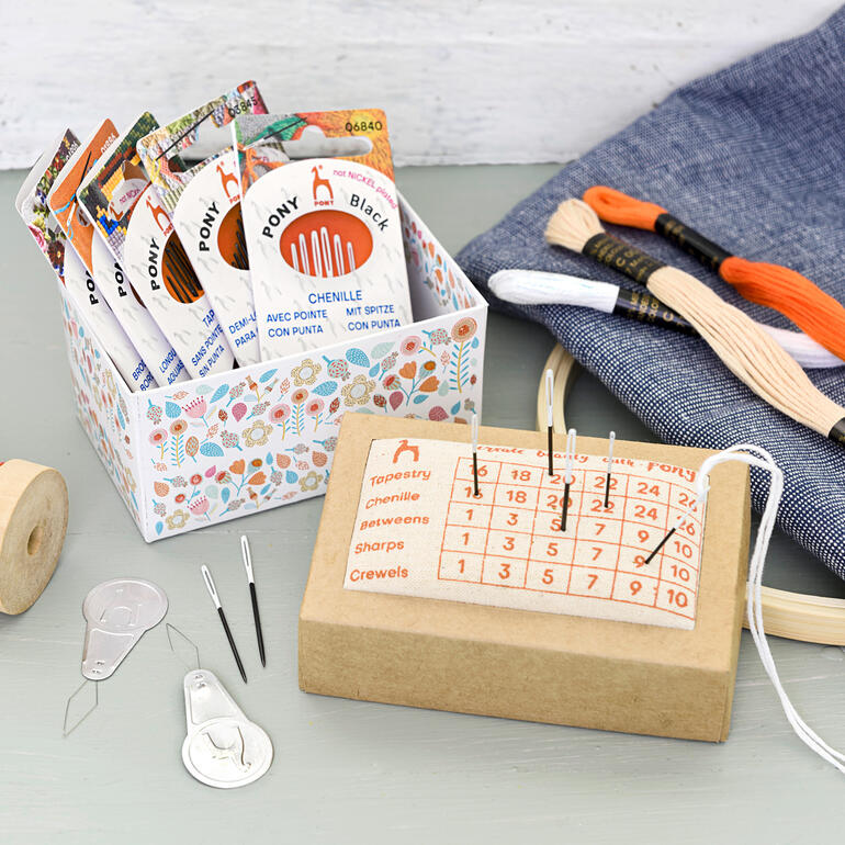 Nähkästchen mit verschiedenen Nähnadeln und Garn zusammen auf einem Tisch.