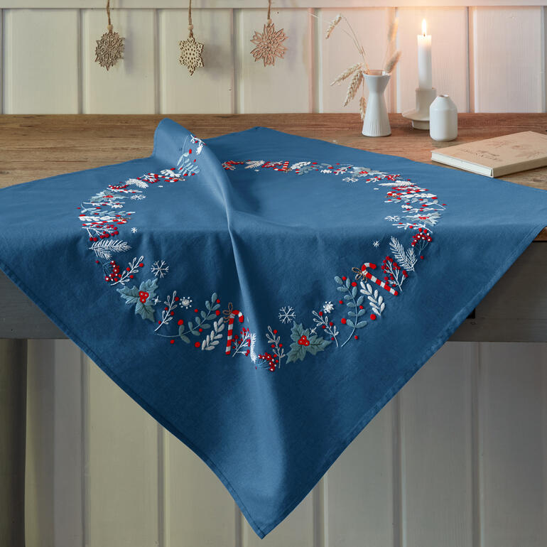 Tischdecke in Blau mit roter und weißer Winterdekoration.