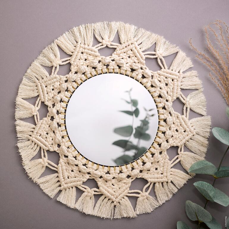 Runder Wandspiegel umgeben von einer makrameeartigen Umrandung.