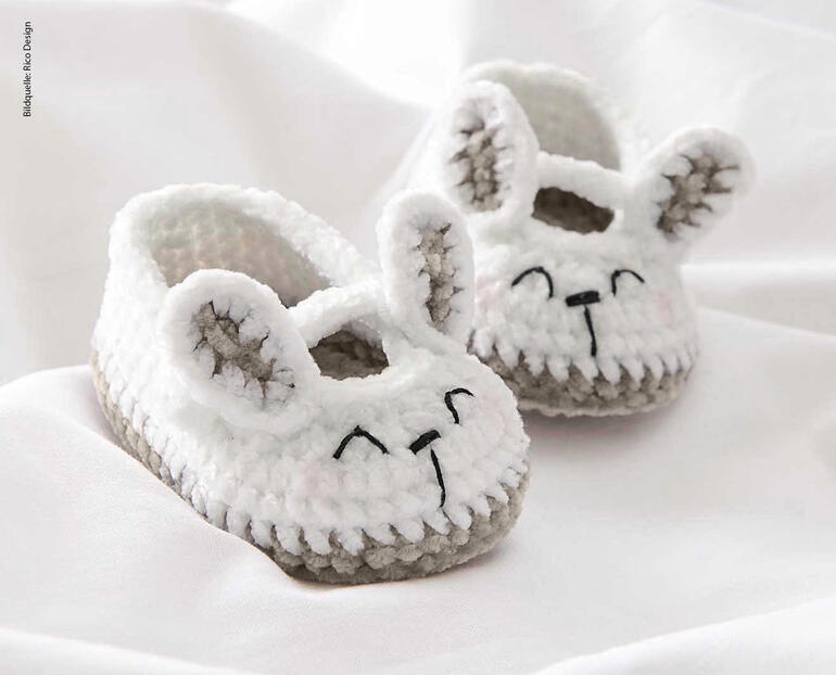 Gehaekelte Baby Booties in Hasenform auf weißem Stoff