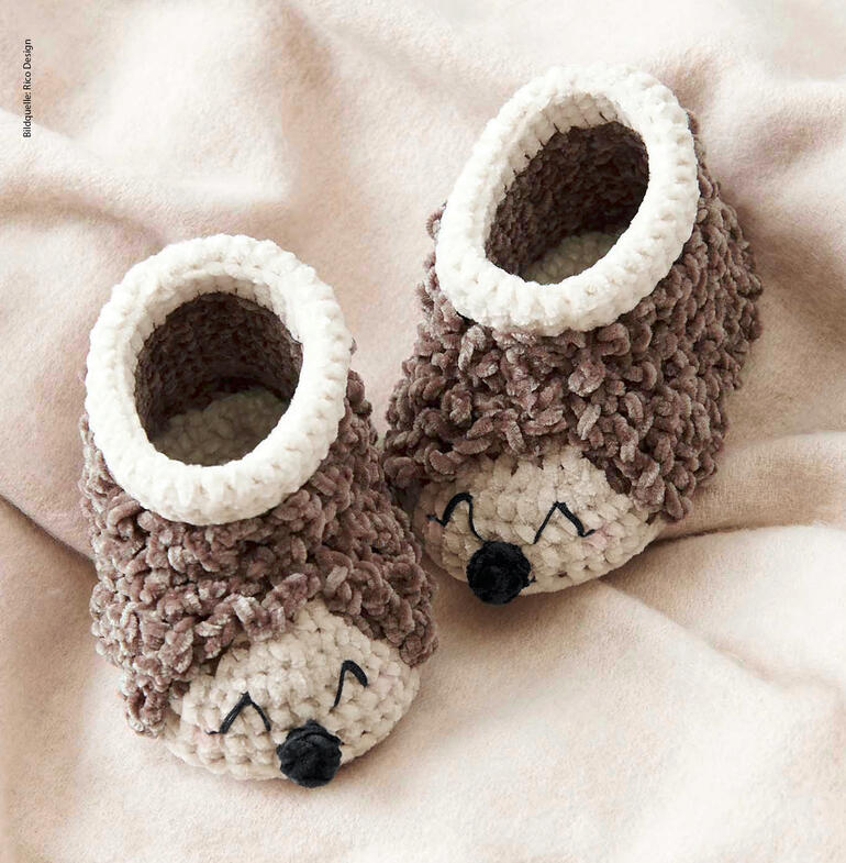 Häkel-Baby-Booties in Form von Igeln mit Stacheln und lächelndem Gesicht.