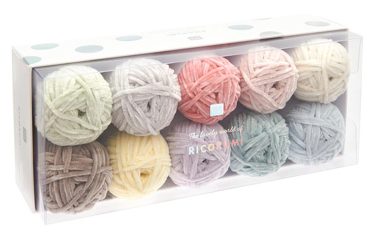 Zehn Pastell-Wollknäuel im transparenten Karton.