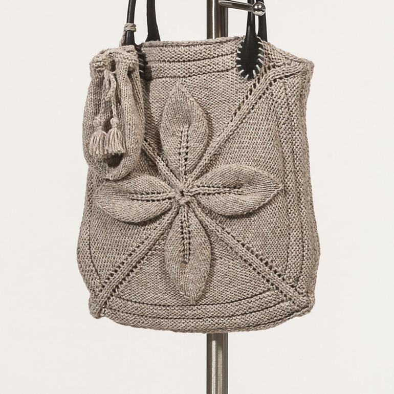 Taschenüberzug aus gestrickten Motiven und kleiner Strickbeutel in neutralen Farben.