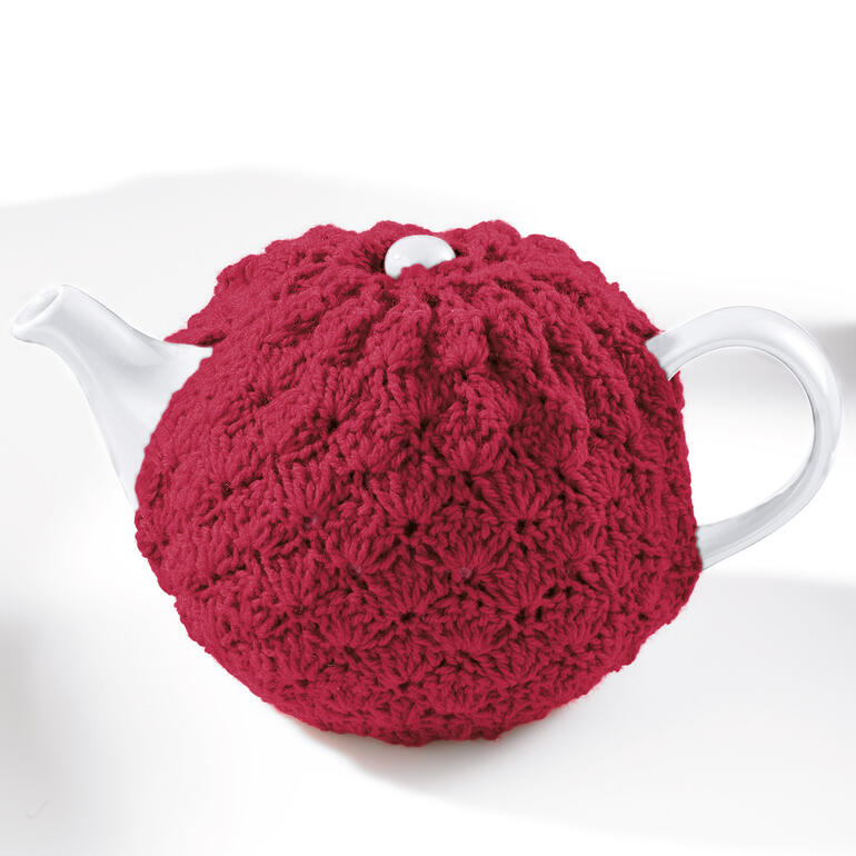 Teekannenwärmer in kräftigem Rot, mit einem strukturierten Muster auf einer weißen Teekanne.