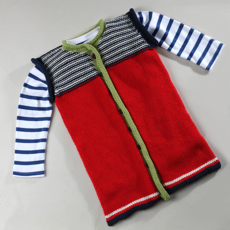 Schlafsack aus Merino-Cotton mit Rollrandblende in Rot und gestreiften Ärmeln.