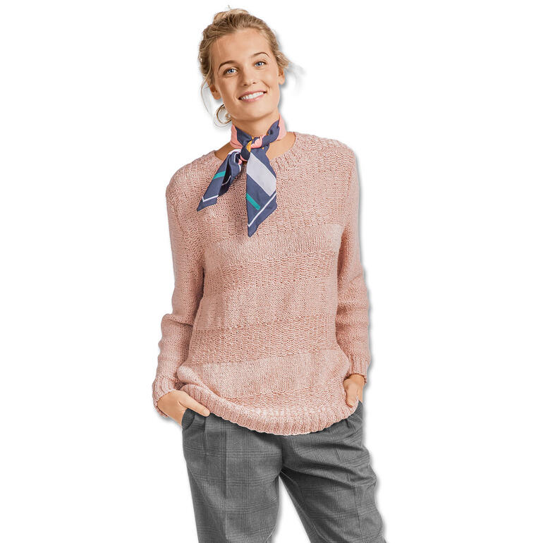 Frau im puderroten Pullover mit Struktur, posiert mit einem gepflegten Look auf neutralem Hintergrund.