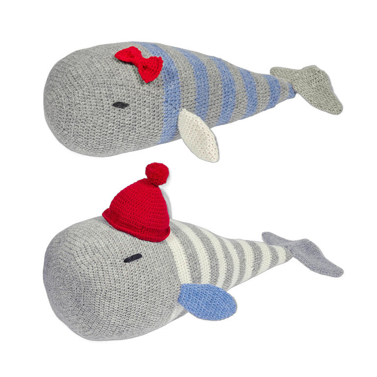 Zwei Häkelwale, einer mit roter Schleife und der andere mit rotem Bommelhut.