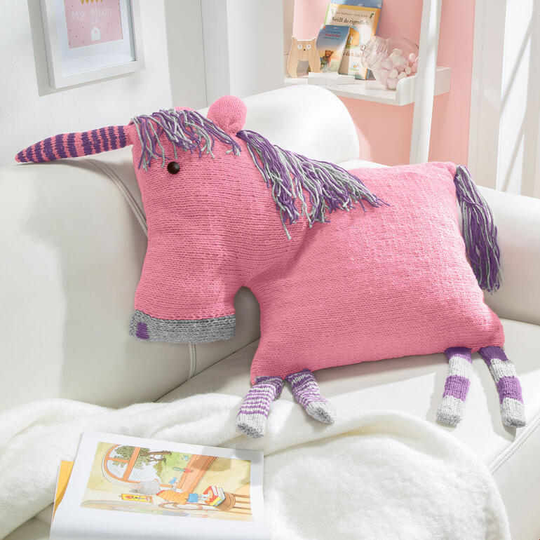 Rosa Einhornkissen auf einer hellen Couch mit bunten Haaren