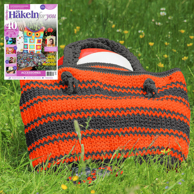 Gestreifte Tasche auf einer Wiese, dekoriert mit einem Magazin