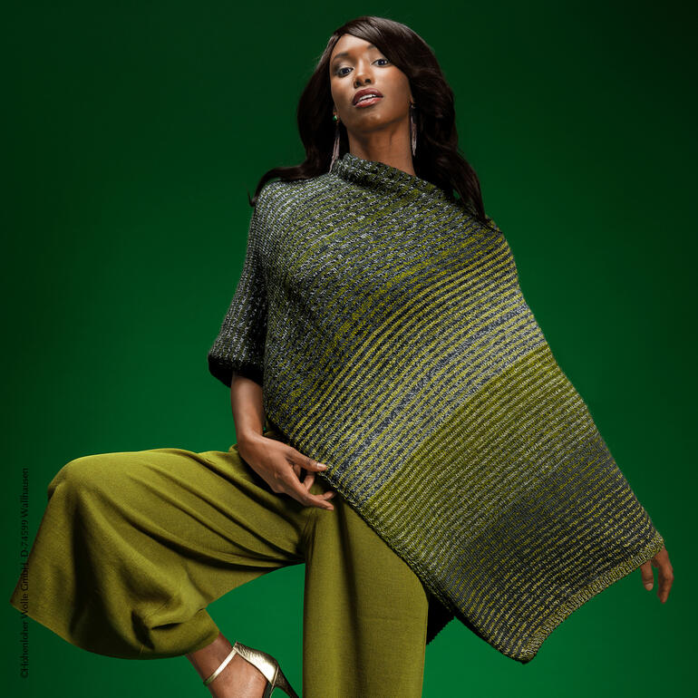 Poncho aus Zauberwolle in Grüntönen, über einem modischen Outfit getragen.