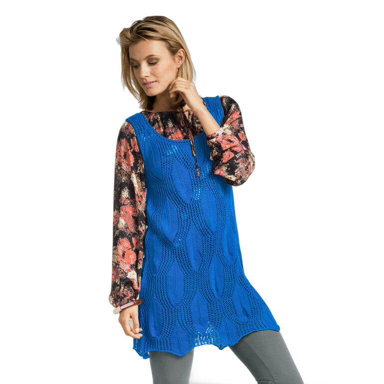 Frau in blauer Tunika mit floralem Unterhemd und grauen Hosen