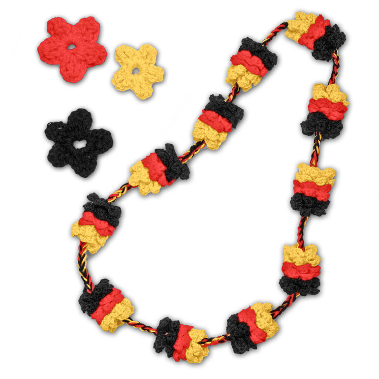 Bunte Fankette mit schwarz, rot und gold, daneben ein paar Blumen aus Wolle.